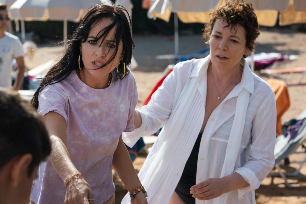 One woman with hoop earrings looks agitated while another holds her back gently. 