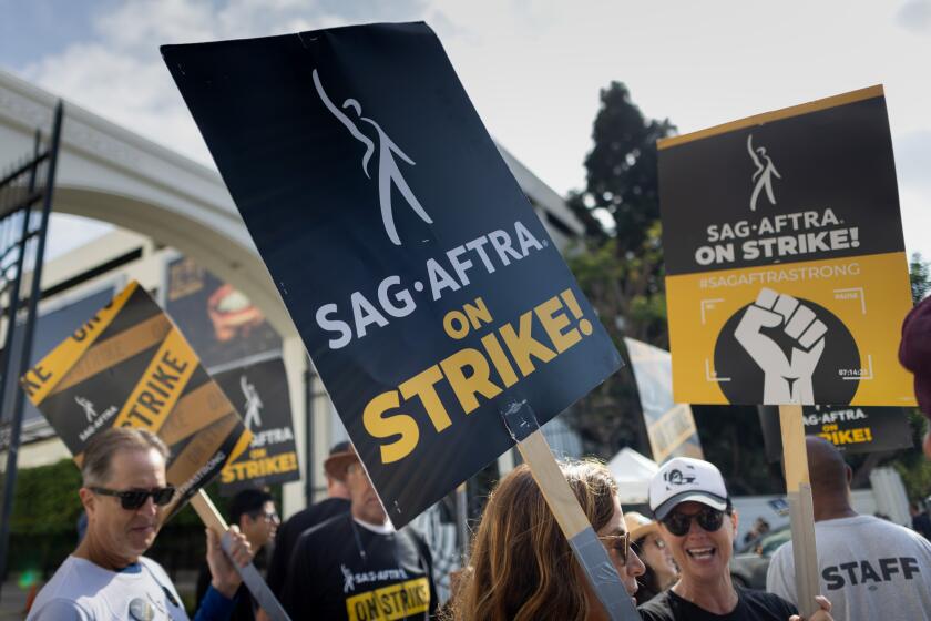 Striking actors carrying picket signs that read, "SAG-AFRTA on strike."