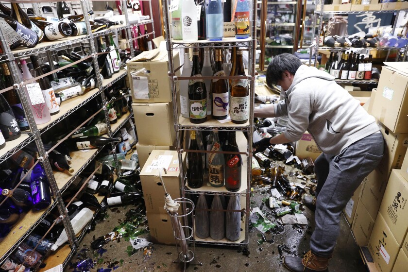 A man clears damaged bottles in a liquor store
