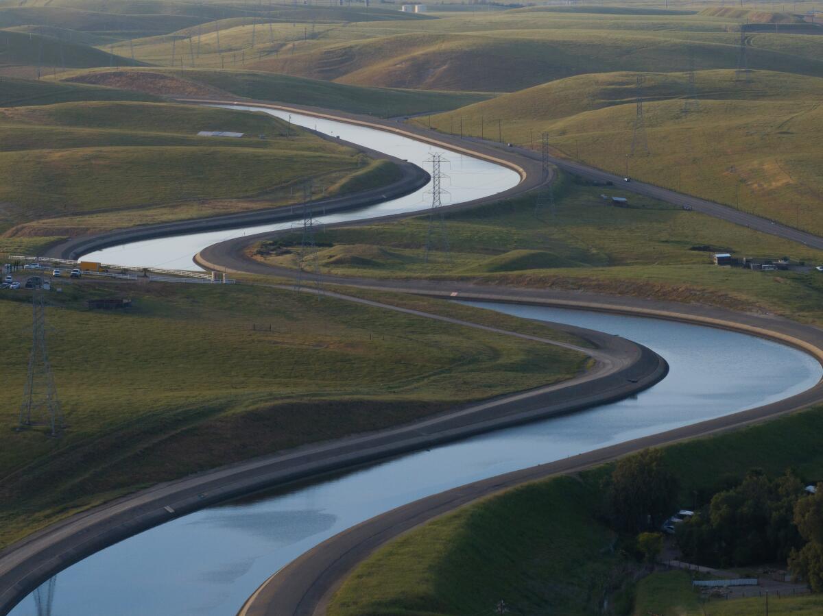 A view of a water channel that runs through a hilly, brown landscape