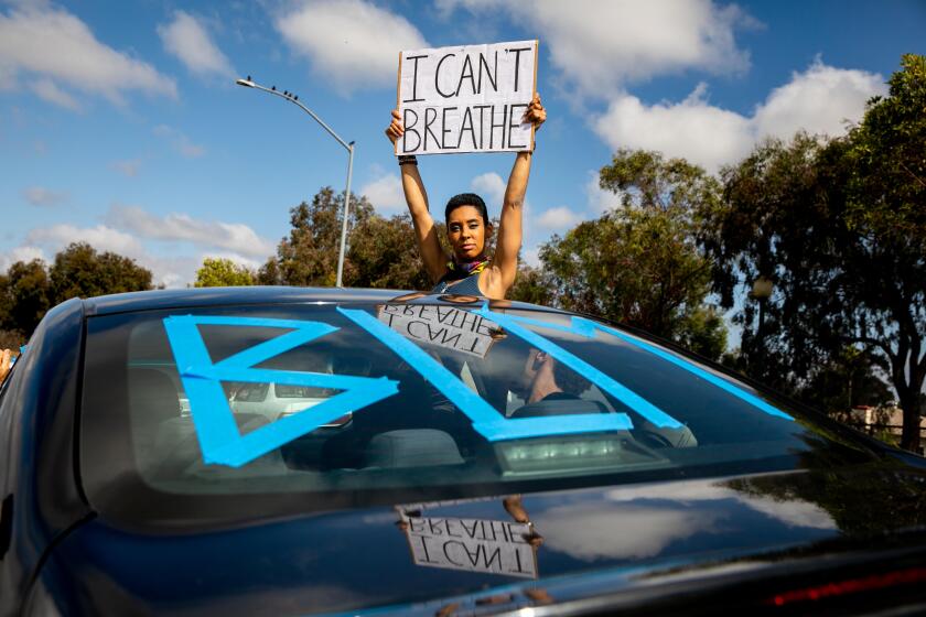 Alexis Horton watches as breakdancers perform at the corner of 50th Street and University Avenue as a caravan of Black Lives Matter protesters drives along the thoroughfare on June 6, 2020 in San Diego, California.