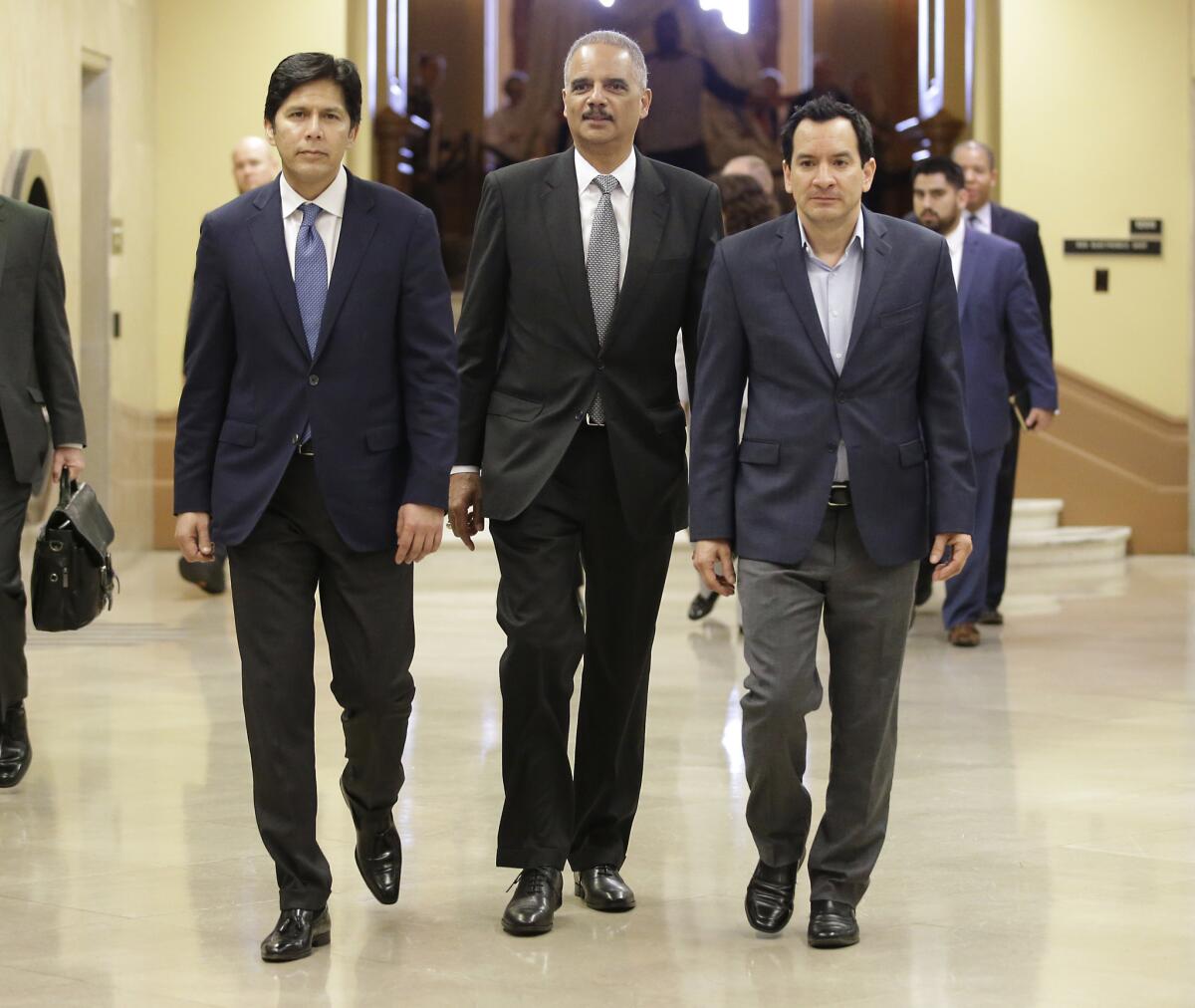 Former U.S. Atty. Gen. Eric Holder, center, flanked by California Senate President Pro Tem Kevin de León (D-Los Angeles), left, and Assembly Speaker Anthony Rendon (D-Paramount) walks to a meeting with Gov. Jerry Brown on Feb. 7 in Sacramento.
