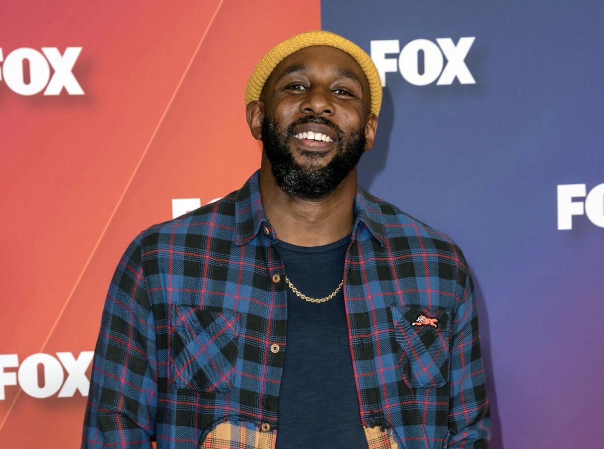 A smiling man in a plaid shirt and yellow beanie