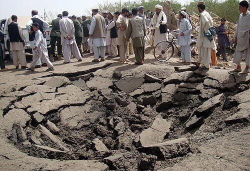 Local residents in Afghanistan's Logar province inspect the crater created when a truck carrying a bomb tipped over and the device exploded.