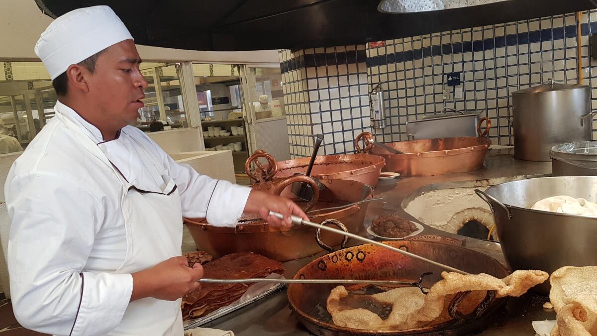 A cook dips pig skin into sizzling oil at Arroyo Restaurant. Each weekend, chefs prepare 44 pounds of chicharon.