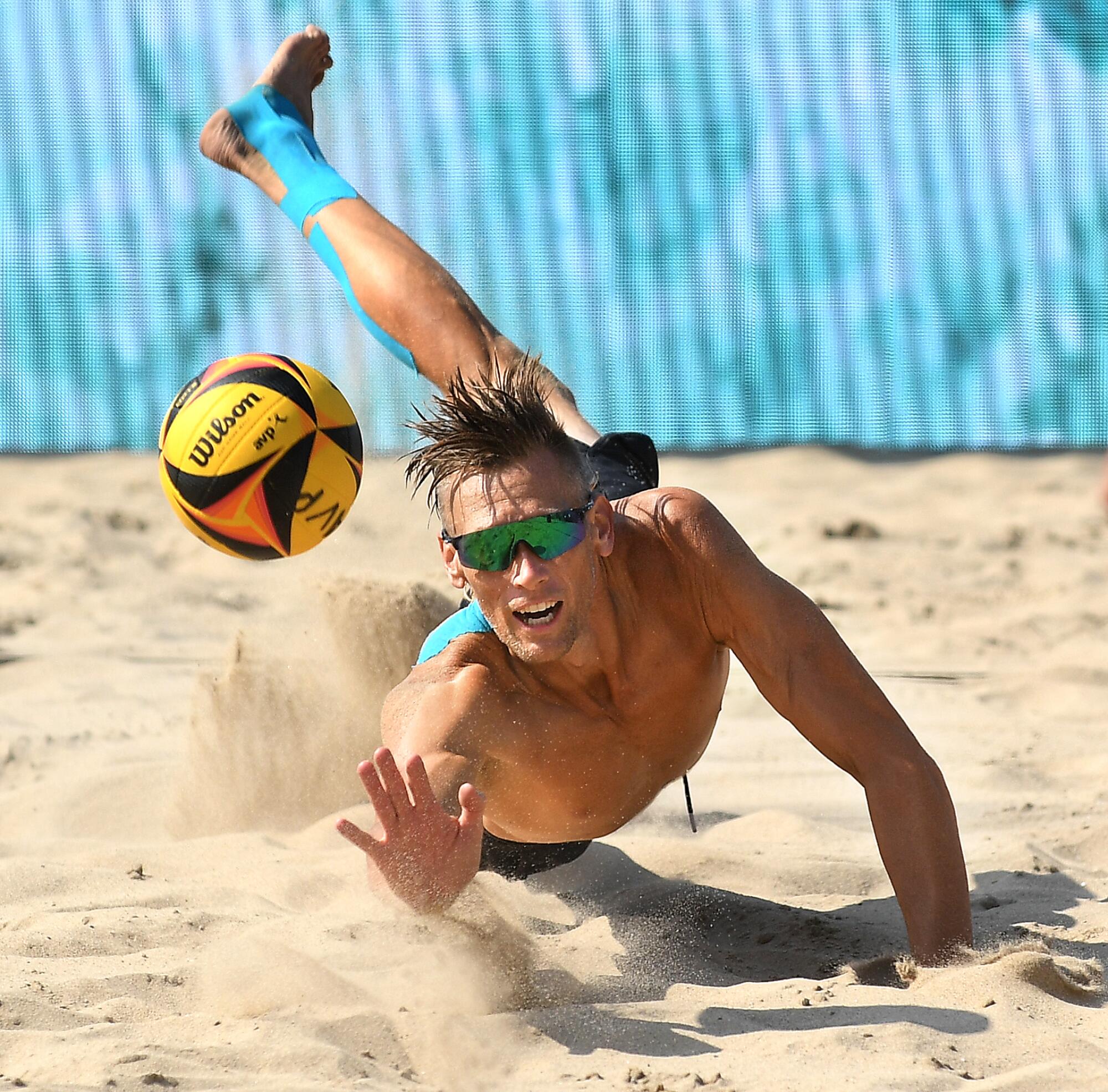 Casey Patterson dives into the sand to keep a volleyball from hitting the ground.