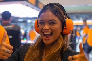 Bianca Bustamante gives a thumbs up while standing in the McLaren garage during a Formula One race weekend.