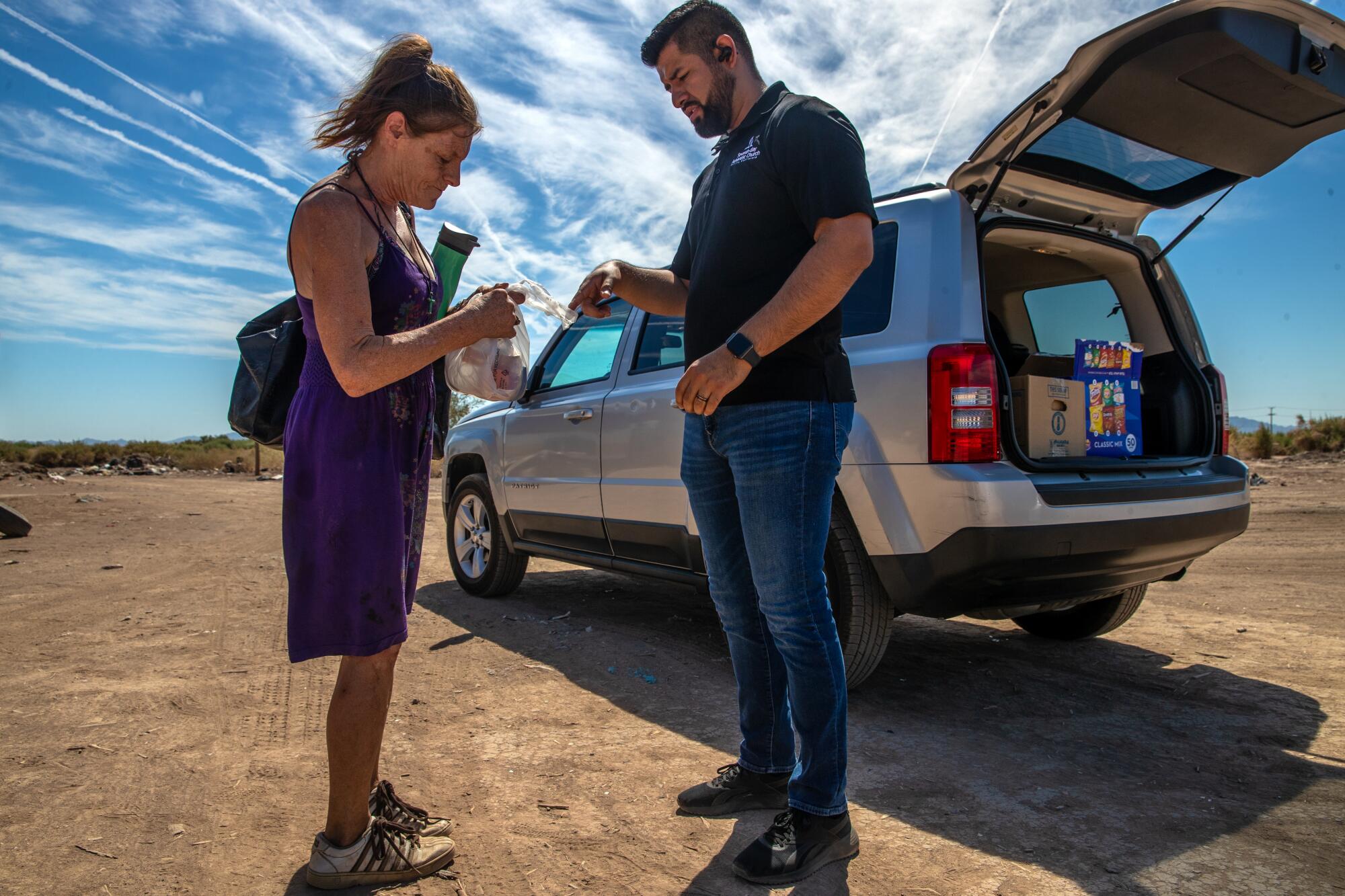 A man gives food to a woman on a very hot day in Blythe.