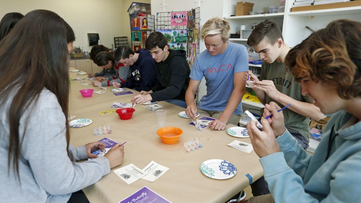 Students from Sage Hill School in Newport Coast paint ceramic butterflies as they participate in the Butterfly Project to honor the children killed during the Holocaust.