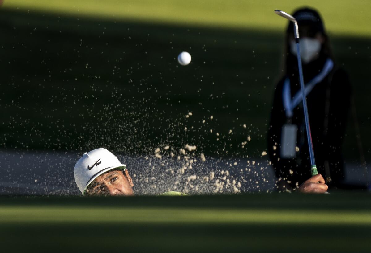 Tony Finau hits out of a bunker during a second playoff hole against Max Homa.