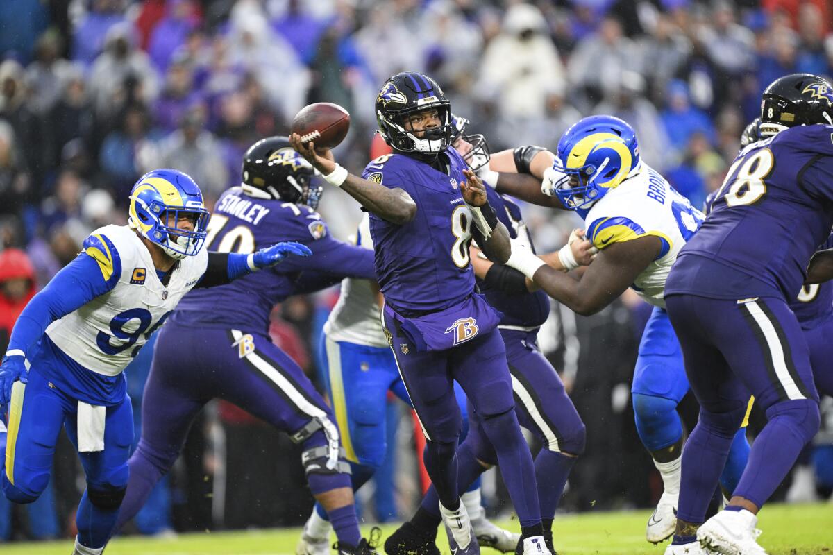  Ravens quarterback Lamar Jackson (8) throws despite pressure from the Rams defense.