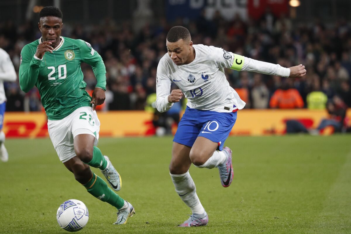 France's Kylian Mbappe, right, and Ireland's Chiedozie Ogbene compete for the ball during the Euro 2024 group B qualifying soccer match between Ireland and France at the Aviva Stadium in Dublin, Ireland, Monday, March 27, 2023. (AP Photo/Peter Morrison)