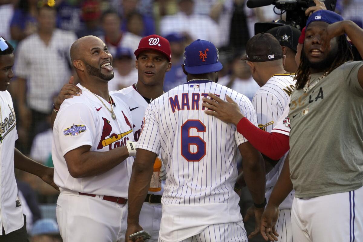Albert Pujols, of the St. Louis Cardinals, left, is hugged by teammates during the MLB All-Star Home Run Derby.