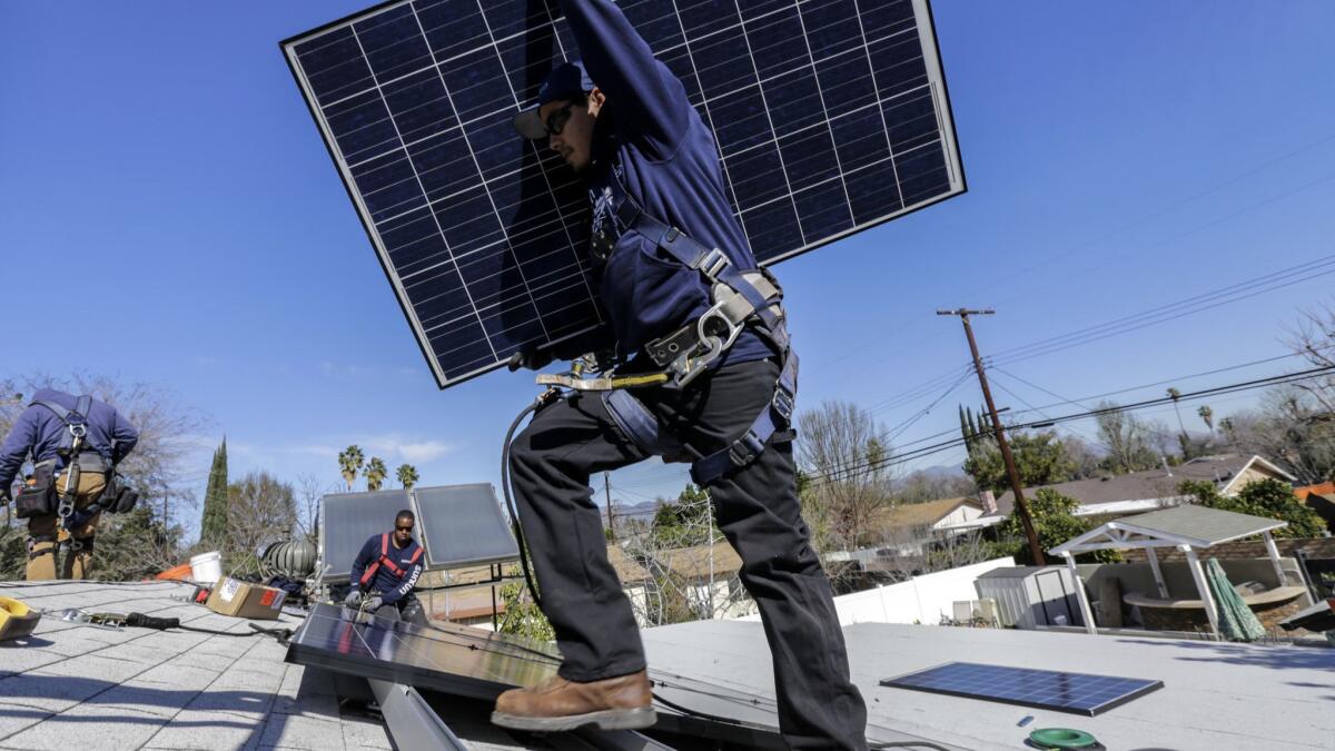 Alejandro DeLeon carries a solar panel as workers from home solar company Sunrun install a system on a home in Van Nuys.