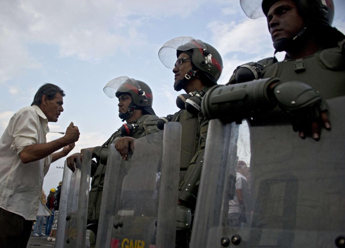 A man talks with members of the Venezuelan National Guard on Friday in the city of San Cristobal. At least eight people have been killed and 137 wounded in two weeks of protests, officials said.