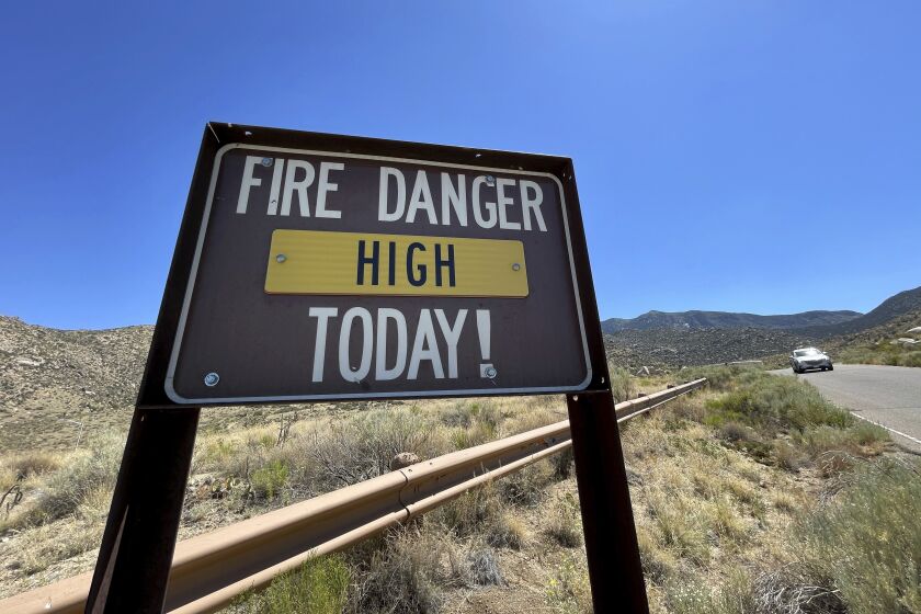 A sign warns that fire danger is high in the foothills of the Sandia Mountains that border Albuquerque, N.M., on Friday, June 30, 2023. U.S. Forest Service managers are urging people to use glow sticks and cans of aerosol party string as alternatives to fireworks, but some environmentalists say the string is difficult to clean up and should not be used out in nature. (AP Photo/Susan Montoya Bryan)
