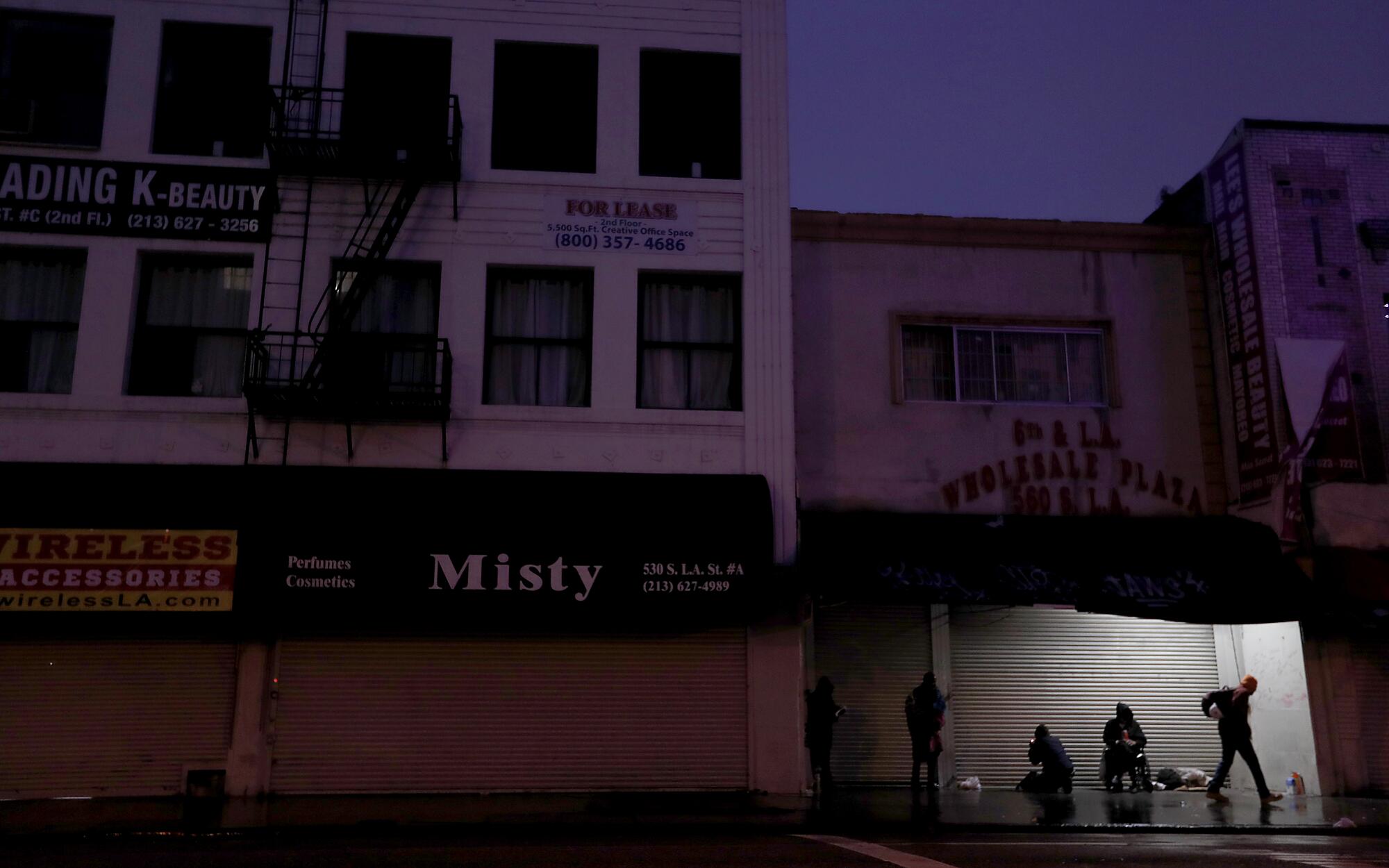 Homeless men gather under awnings of shuttered businesses along Los Angeles Street in the downtown garment district.