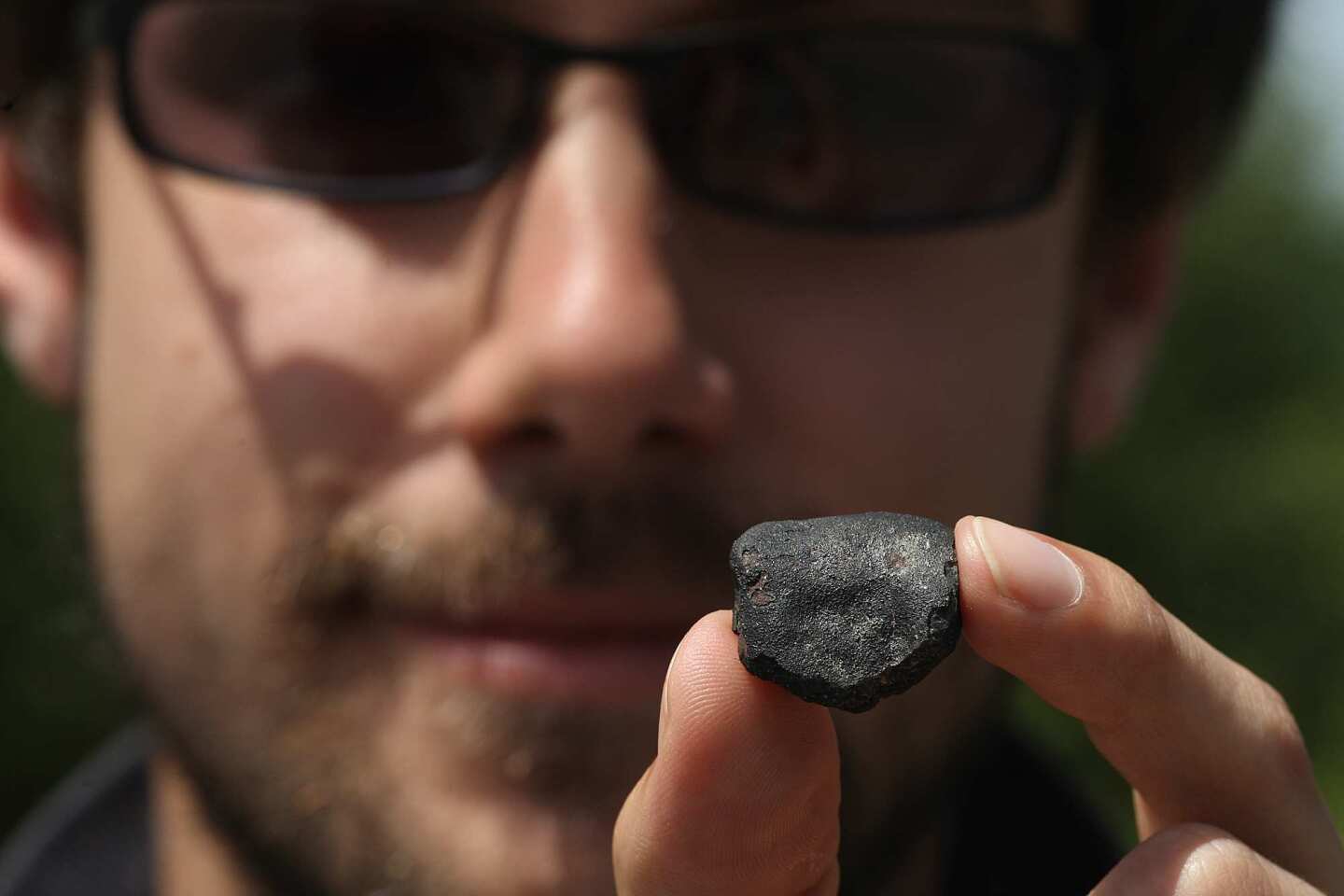 Jason Utas, a geology student at UC Berkeley, holds a 7.5-gram fragment of a meteorite called CM chondrite he found Friday in Coloma, Calif. He was among the many people who descended into the area following a fireball on April 22. Utas found the fragment in the David Moore Nature Area off Highway 49, just west of Coloma. Scientists used weather radar to track the movements of the object and predicted it fell near Coloma. The meteorite is a rare class that contains water and carbon compounds that are similar to those responsible for producing life on Earth. It is in this location that gold was first discovered in 1848.