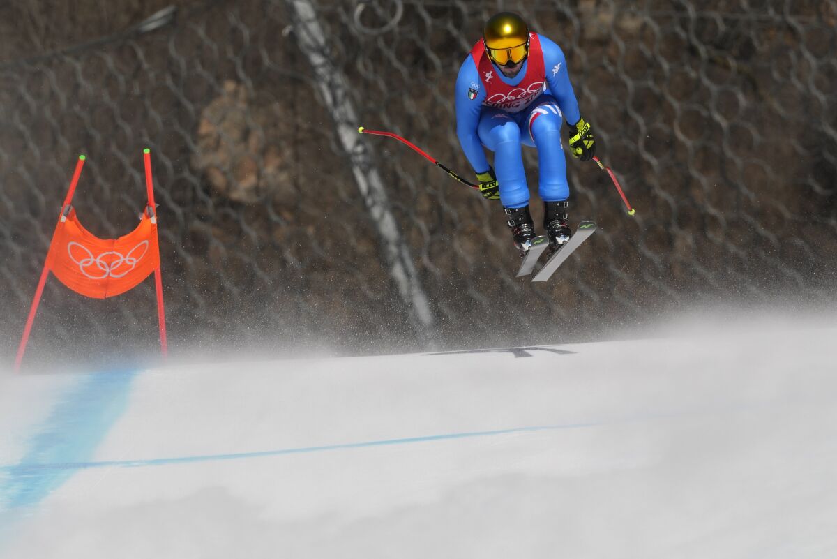 Snow blows across the course as Dominik Paris of Italy makes a jump during men's downhill training at the 2022 Winter Olympics, Friday, Feb. 4, 2022, in the Yanqing district of Beijing. (AP Photo/Luca Bruno)