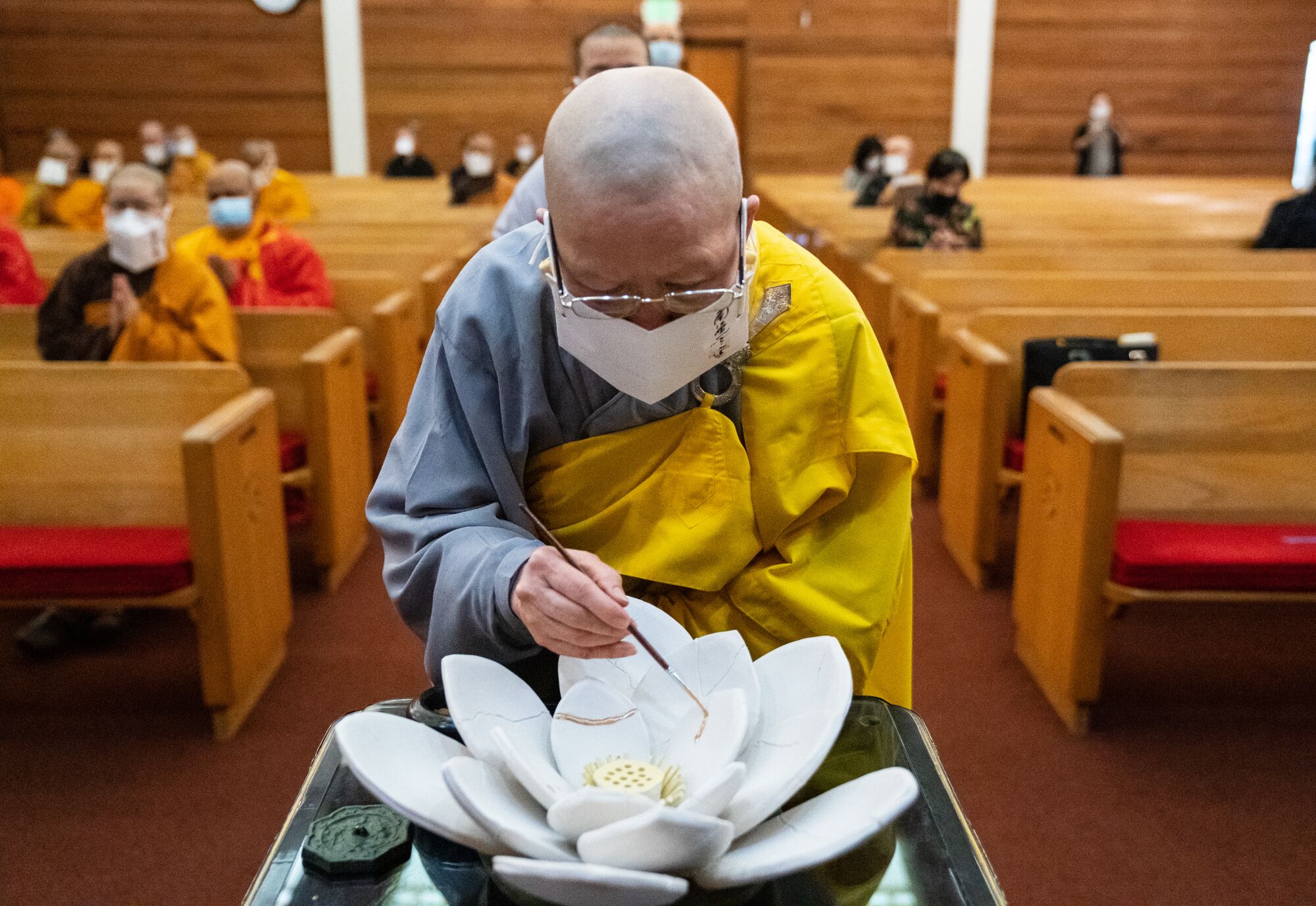 A Buddhist priest gilds a ceramic lotus flower