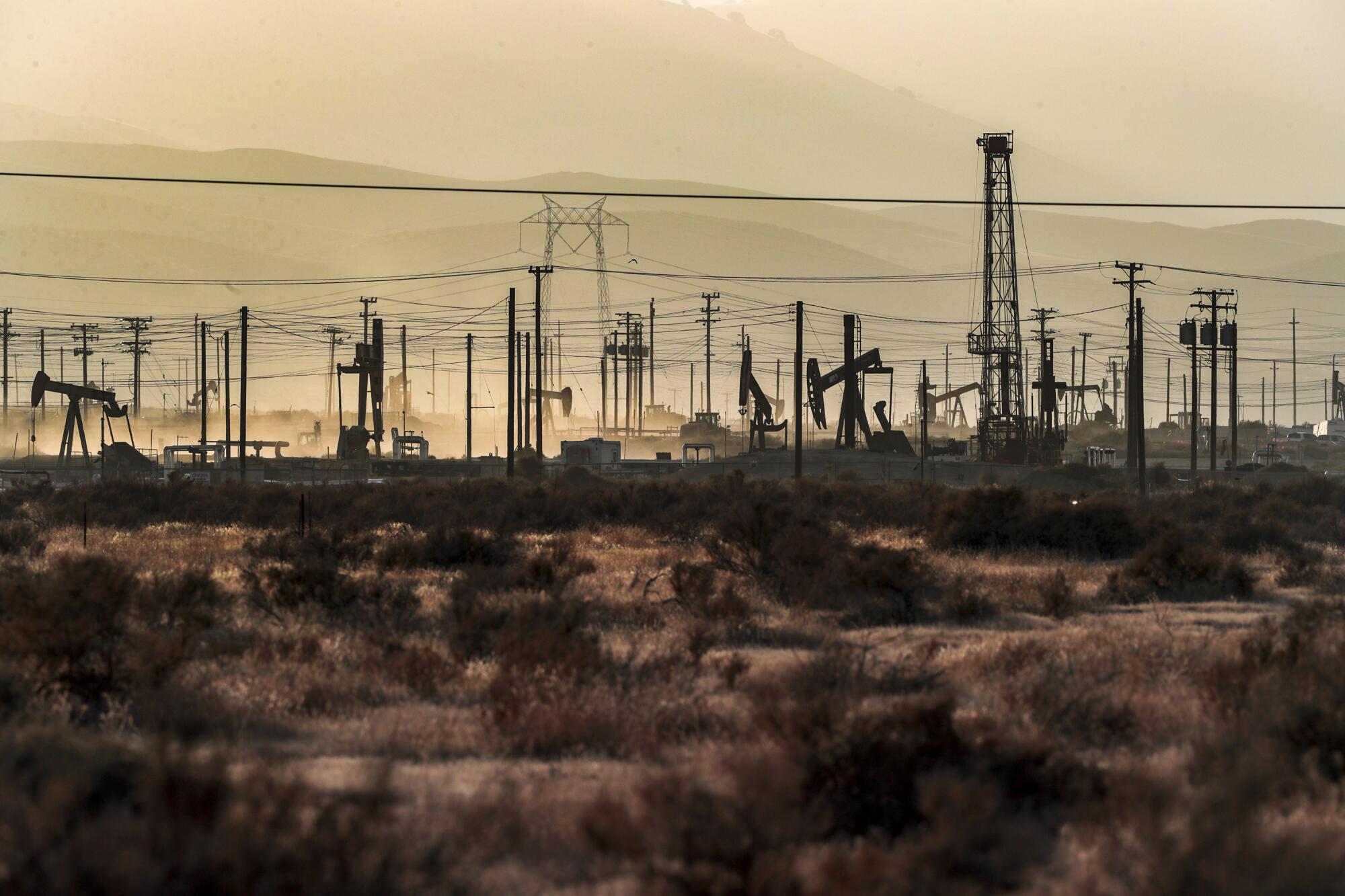 Oil pumpjacks and power lines fill a desert landscape.