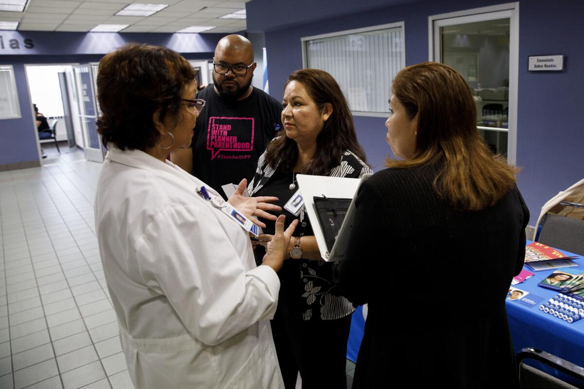 In an examination area set up at the Mexican Consulate, Planned Parenthood nurse practitioner Teresa Arellano, left, speaks with outreach director Fortina Hernandez and Lorena Ojeda, who gives presentations at the consulate.