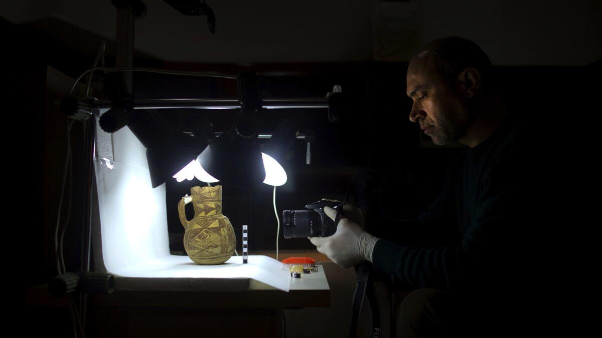 An archaeologist at the National Museum in Damascus examines an artifact rescued from southern Syria. The appetite for Syria’s artifacts has created an opening for counterfeits.