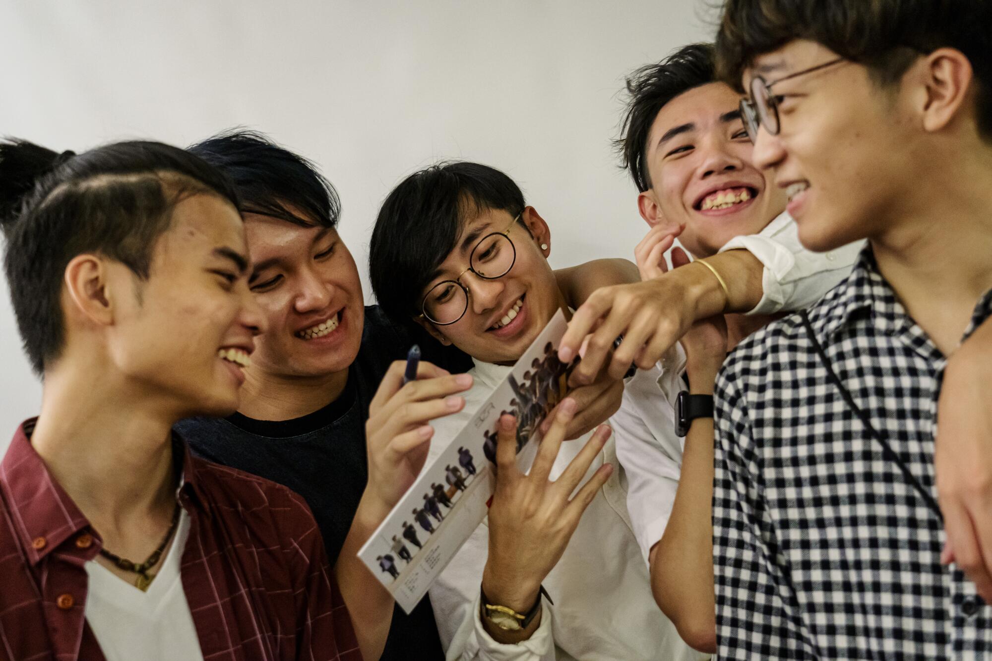 Boyz Reborn members Jason Kwok, left, Kevin Shek, Kenny Cheng, Sam Lee, and Ben Chan sign a CD album for a fan.