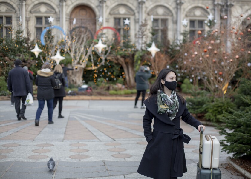 A woman wears a face mask to prevent the spread of the COVID-19 as she walk past in front the City Hall, in Paris, Wednesday, Dec. 8, 2021. (AP Photo/Rafael Yaghobzadeh)