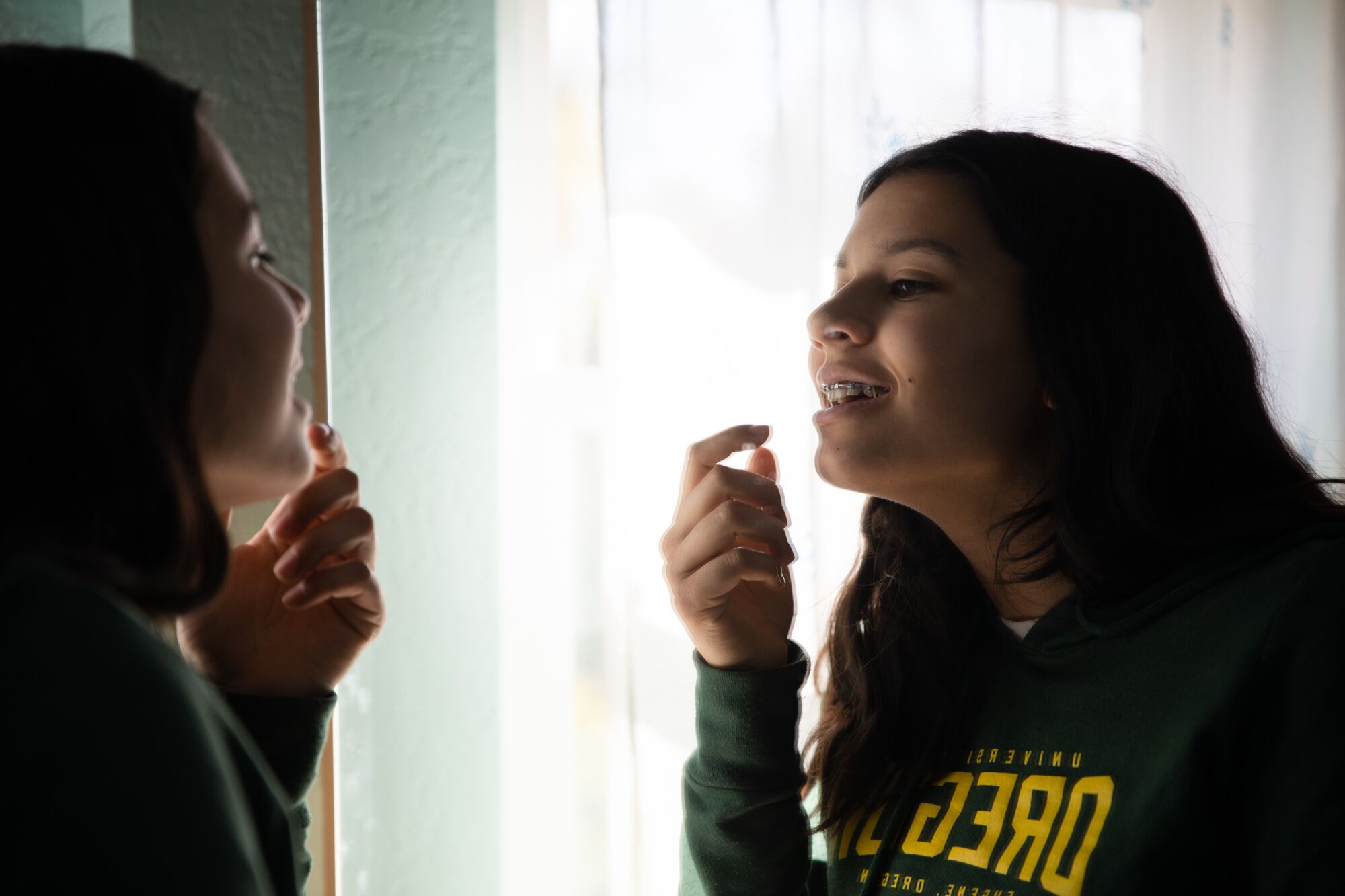 Vishaala Wilkinson looks into a mirror to help attach bands to her braces.