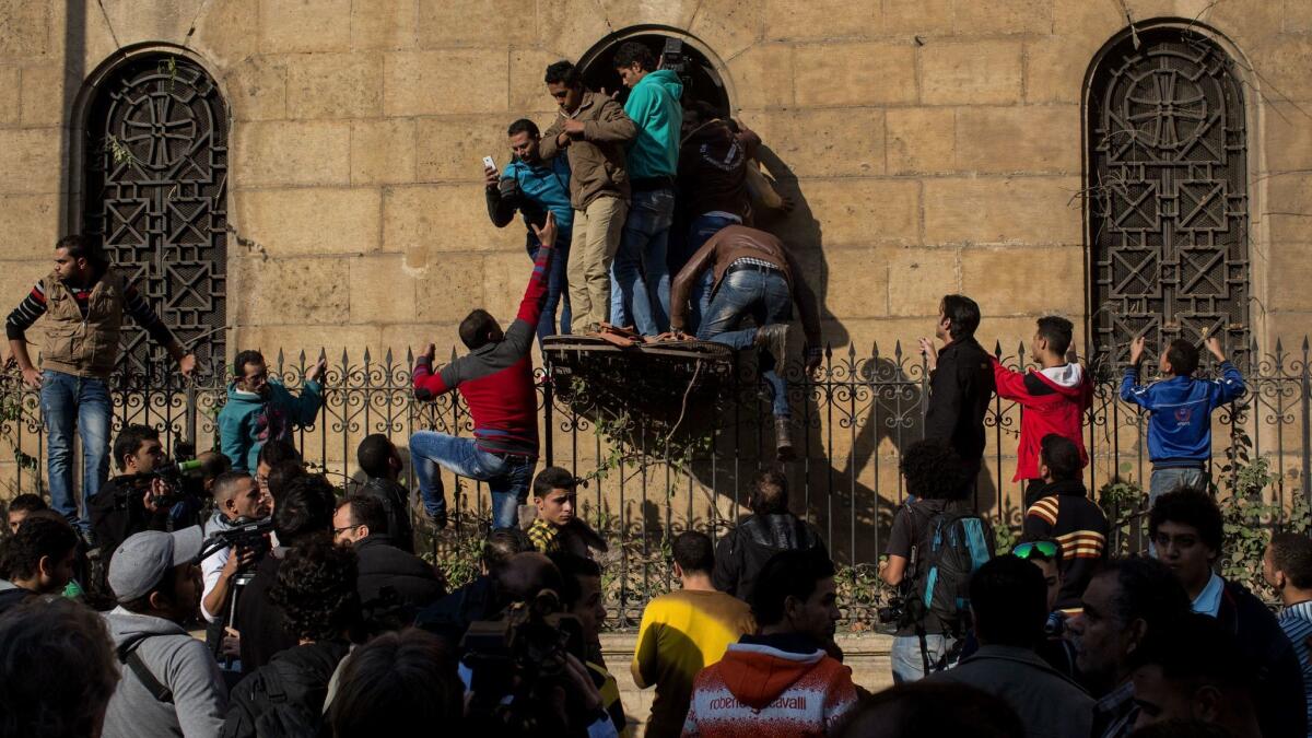 People try to look through a broken window into the destroyed interior of the church of St Peter and St Paul in the Coptic Cathedral complex after a bomb exploded on Dec. 11, 2016 in Cairo.