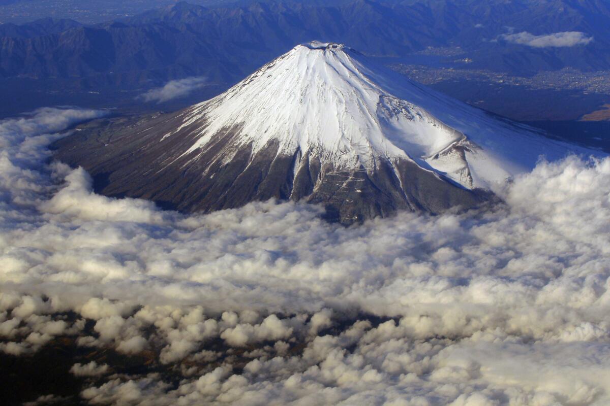 A snow-covered Mt. Fuji is seen from an airplane window.
