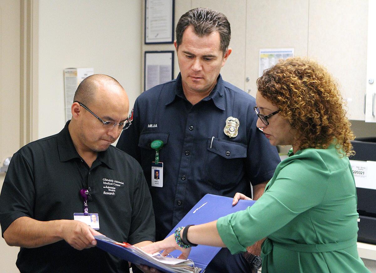 Glendale Adventist Clinical Research Coordinator Javier Valeriano,left, and Director of Integrated Research Lily Villalobos, right, go through patient training material with Glendale firefighter/paramedic Gilberto Mejia on Tuesday, September 1, 2015. The training is to prepare Mejia for home visits to cardiac patients shortly after being released from the hospital. Glendale Adventist and the Glendale Fire Department are the first in California to coordinate like this with the goal to reduce the need for patients to return to the hospital.