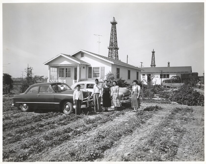 A family on a farm in Torrance, in front of a house and cars
