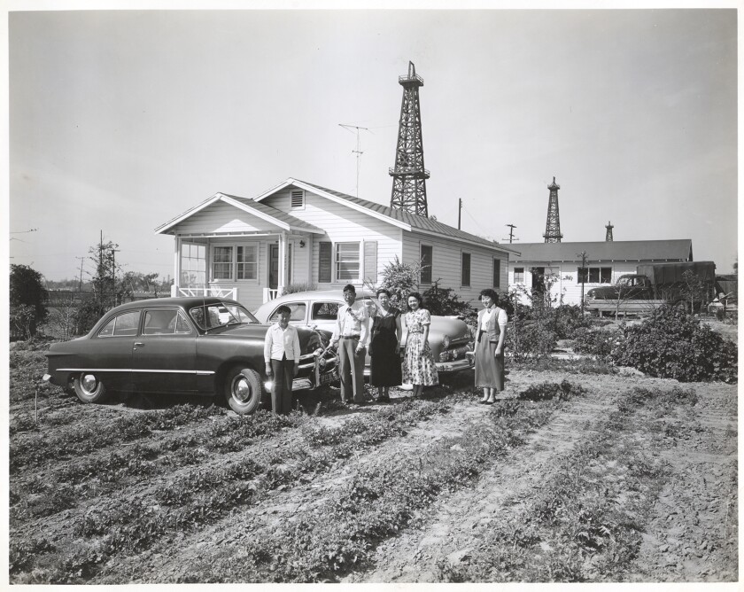 Eine Familie auf einem Bauernhof in Torrance, vor einem Haus und Autos