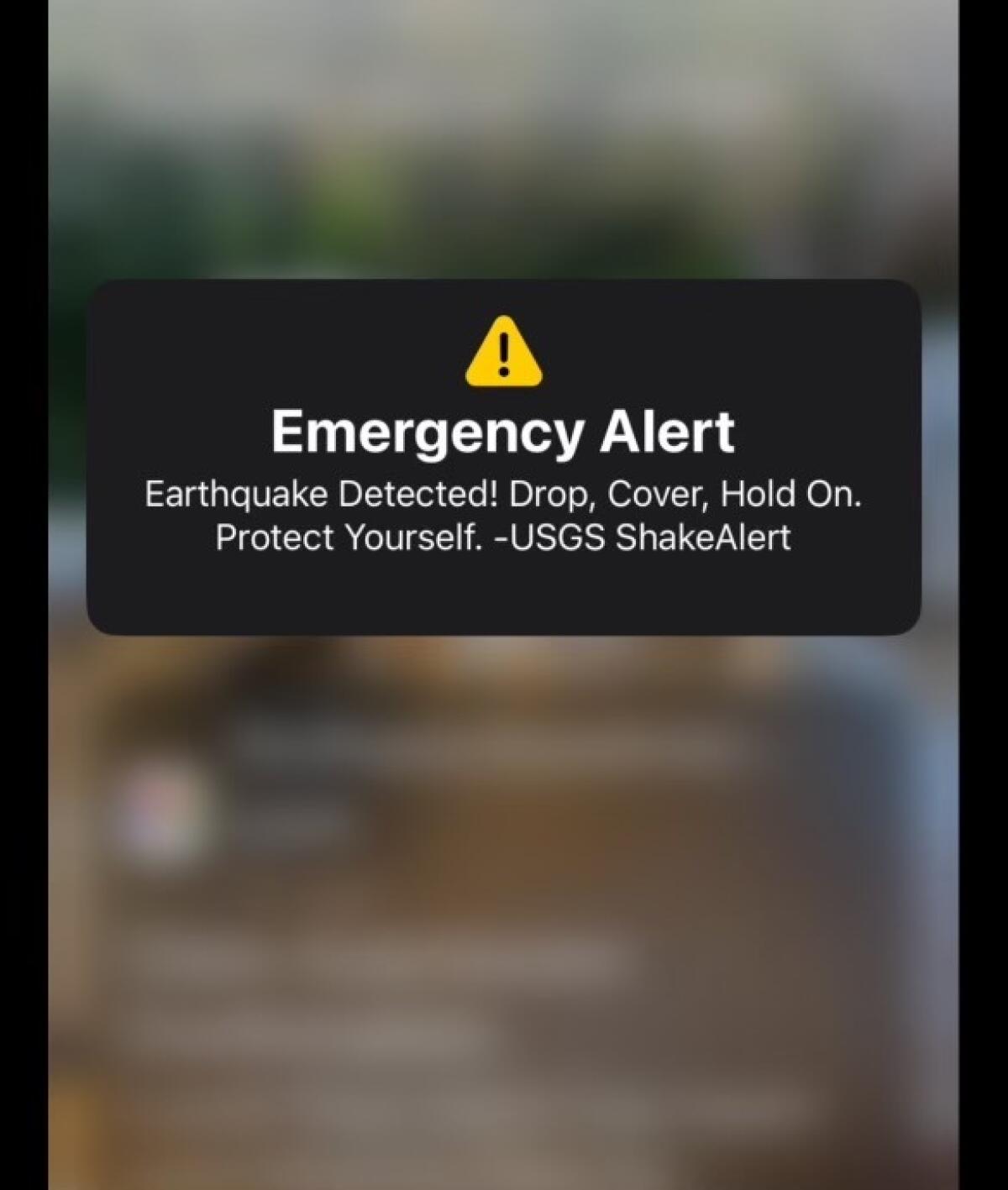 A screenshot with a yellow triangle warning sign above the words "Emergency Alert" and quake information from USGS ShakeAlert