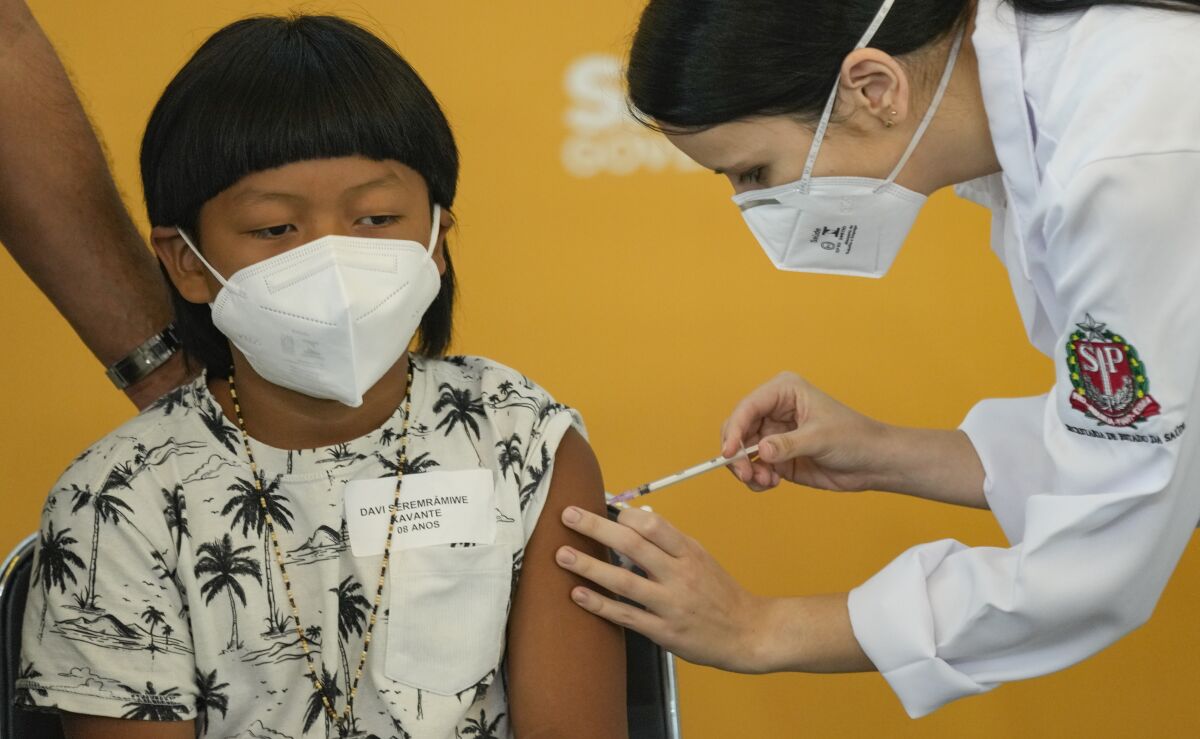 A health worker gives a shot of the Pfizer COVID-19 vaccine to 8-year-old Indigenous youth Davi Seremramiwe Xavante at the Hospital da Clinicas in Sao Paulo, Brazil, Friday, Jan. 14, 2022. The state of Sao Paulo started the COVID-19 vaccination of children between ages 5 and 11. (AP Photo/Andre Penner)