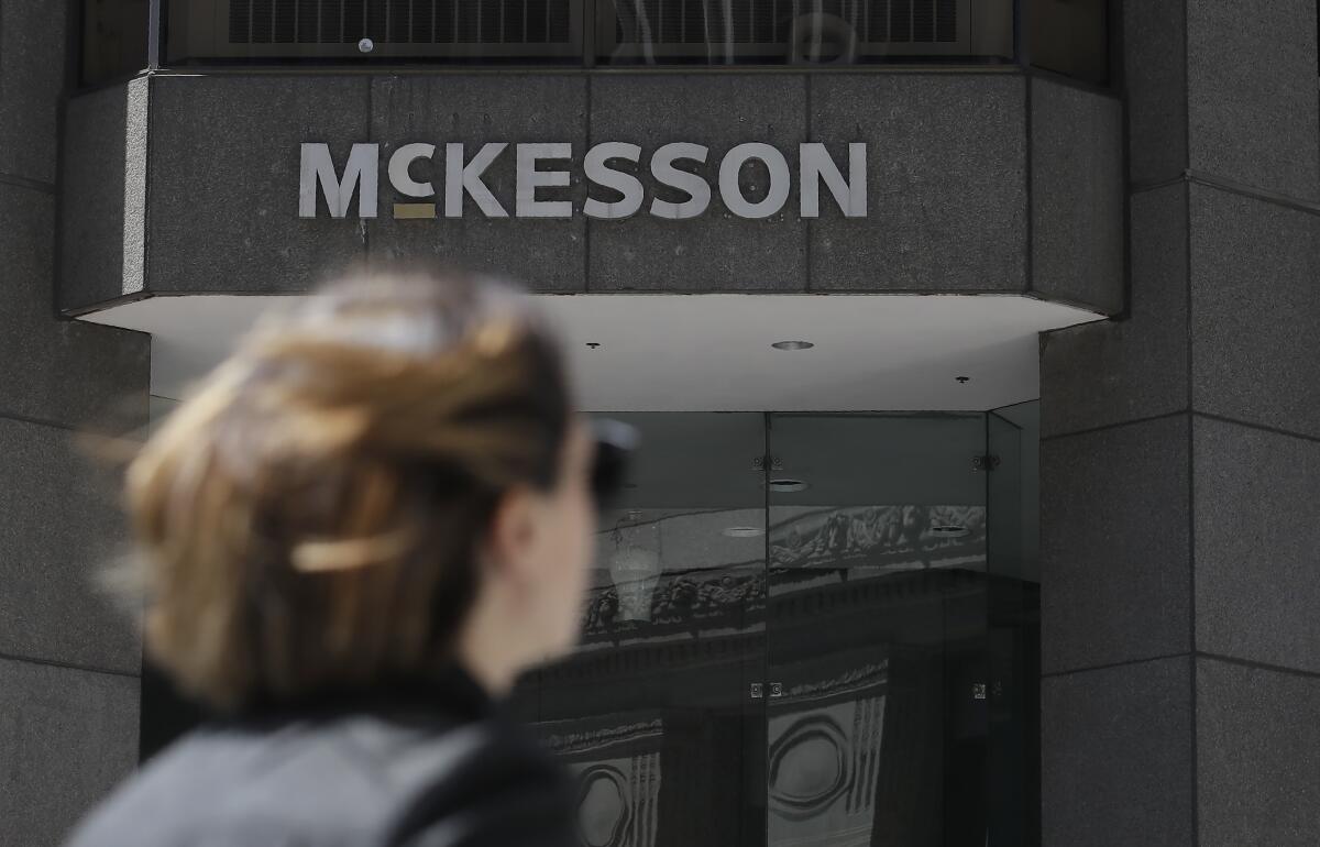FILE - In this July 17, 2019 file photo, a pedestrian passes a McKesson sign on an office building in San Francisco. Four companies say they'll move ahead with a $26 billion settlement of lawsuits over the opioid crisis. An announcement from drug distributors AmerisourceBergen, Cardinal Health and McKesson came Saturday, Sept. 4, 2021. (AP Photo/Jeff Chiu, File)