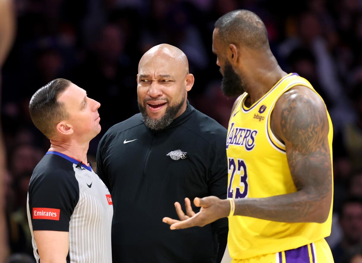 Lakers head coach Darvin Ham, center, and forward LeBron James, right, argue with a referee over a call.