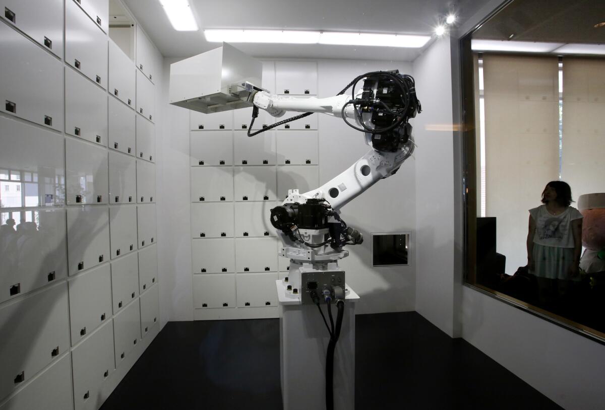 A cloak robot moves a box loaded with items received from a guest during a demonstration for the media at the new hotel, aptly called Henn na Hotel or Weird Hotel, in Sasebo, southwestern Japan, Wednesday, July 15, 2015. From the receptionist that does the check-in and check-out to the porter that's a stand-on-wheels taking luggage up to the room, the hotel, that is run as part of Huis Ten Bosch amusement park, is "manned" almost totally by robots to save labor costs. (AP Photo/Shizuo Kambayashi)