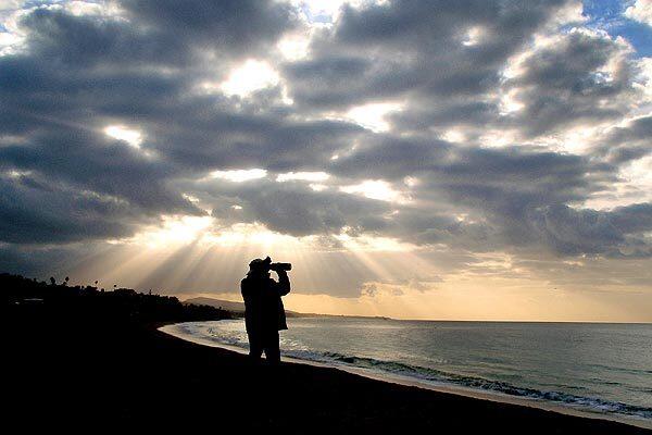 The sun rises behind ominous-looking clouds Sunday in Dana Point. Forecasters expect two storms to hit Southern California this week, starting tonight. Heavy rain would test measures put in place to contain mudslides in neighborhoods left vulnerable by last summer's Station fire in the Angeles National Forest. Full story