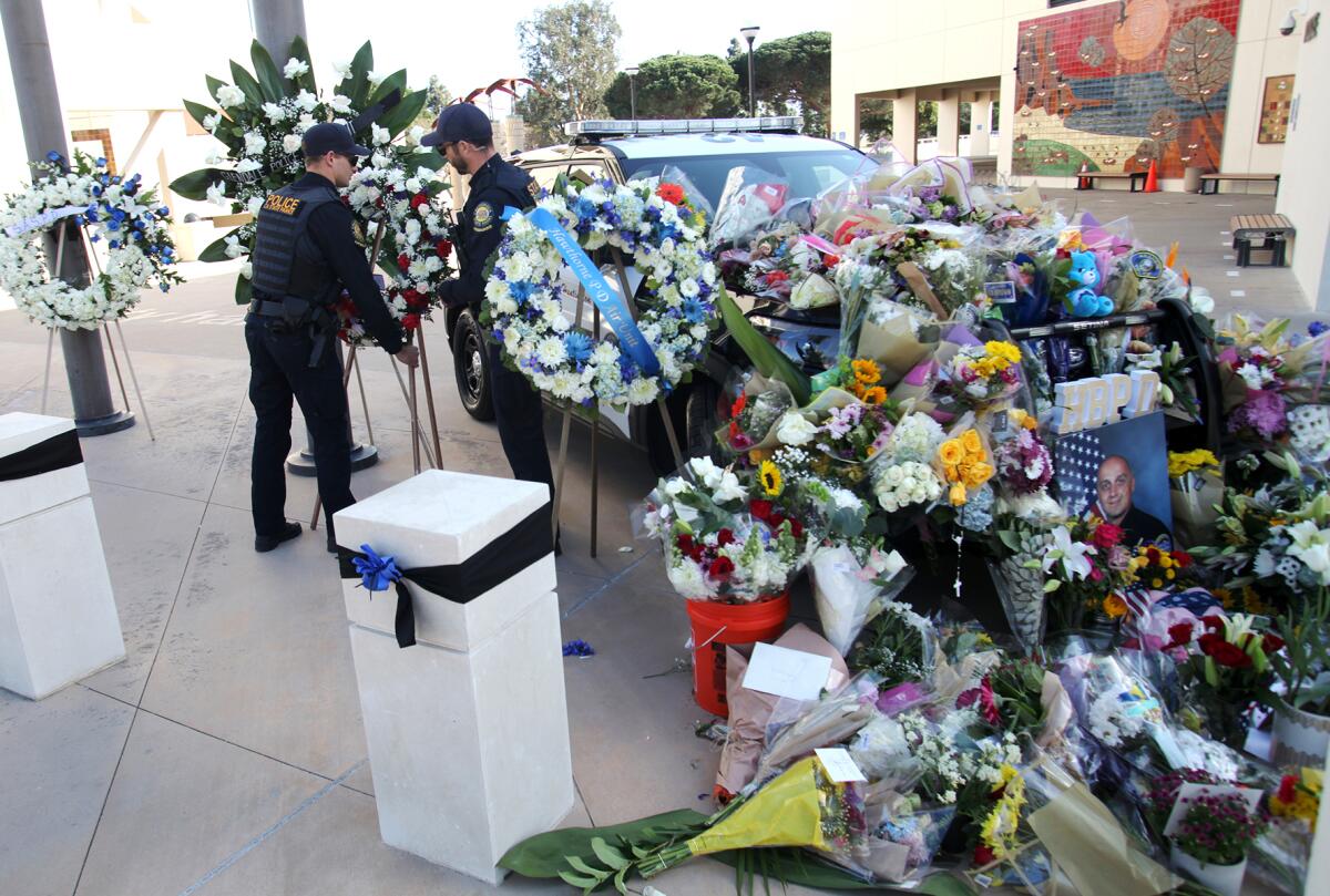 Officers from the California State Parks bring a wreath of flowers to a makeshift memorial for officer Nick Vella.