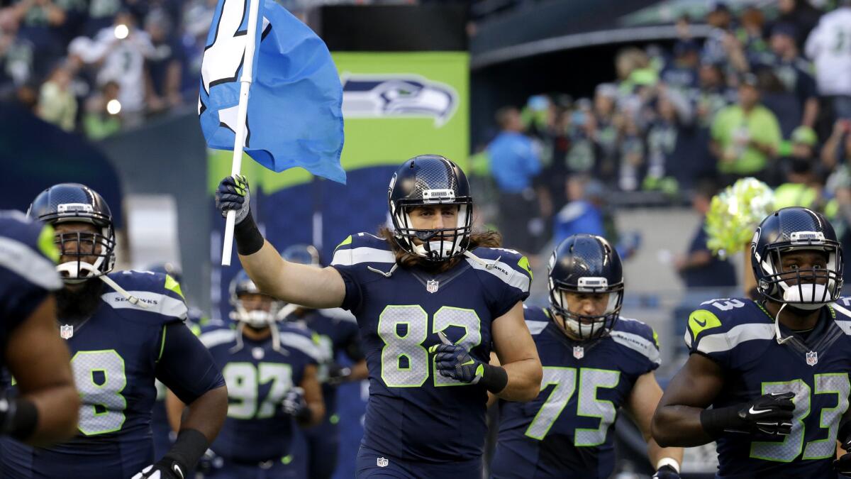 Seahawks tight end Luke Willson carries the 12th man flag as the team runs out of the tunnel before a preseason game against the Raiders.