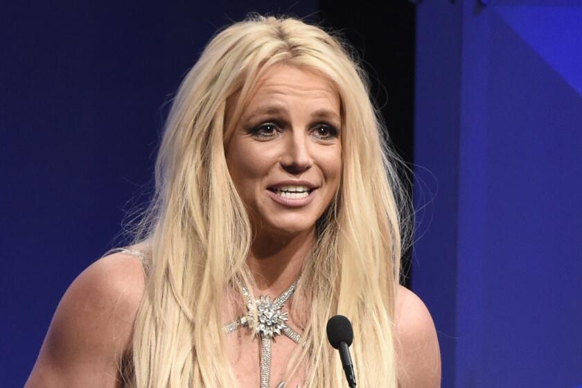 Britney Spears leans in to speak into a standing microphone