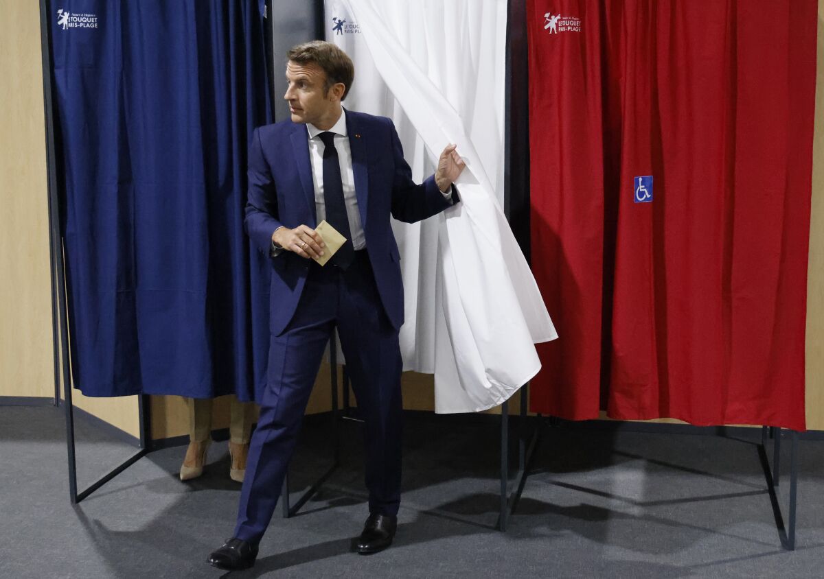 France's President Emmanuel Macron leaves the voting booth before voting in the first round of French parliamentary election at a polling station in Le Touquet, northern France, Sunday June 12, 2022. French voters are choosing lawmakers in a parliamentary election Sunday as President Emmanuel Macron seeks to secure his majority while under growing threat from a leftist coalition. (Ludovic Marin, Pool via AP)