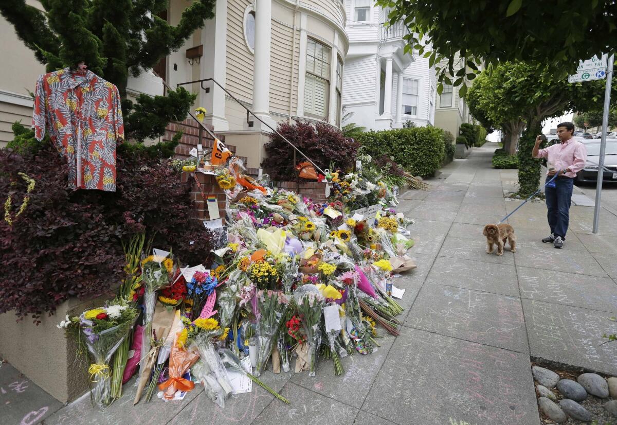 A man stops with his dog to take a picture of a memorial for actor Robin Williams outside the home that was used in the filming of the movie "Mrs. Doubtfire" in San Francisco.