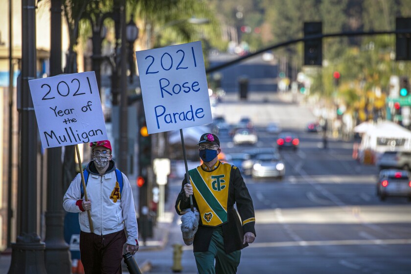Curtis McKendrick, til venstre, og sammen med sin far, Robert McKendrick, bærer skilte langs den tomme Rose Parade-rute.