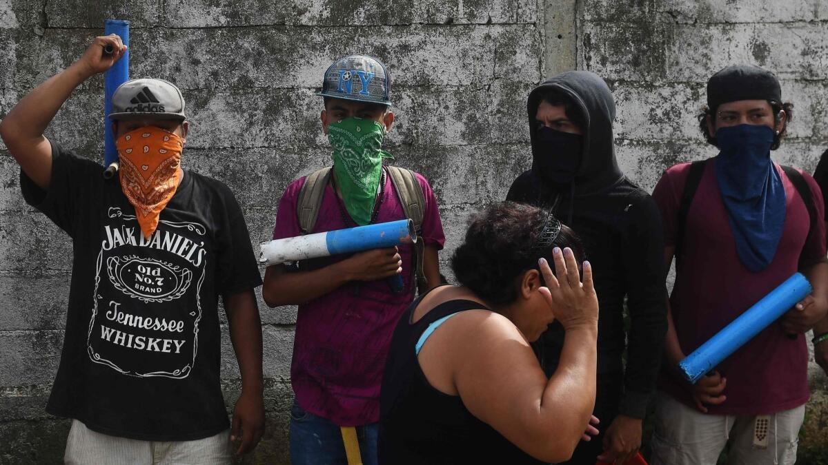 A neighborhood resident walks past a group of members of the "April 19" movement, after leaders of the movement held a news conference in Masaya, Nicaragua, on June 18, 2018.