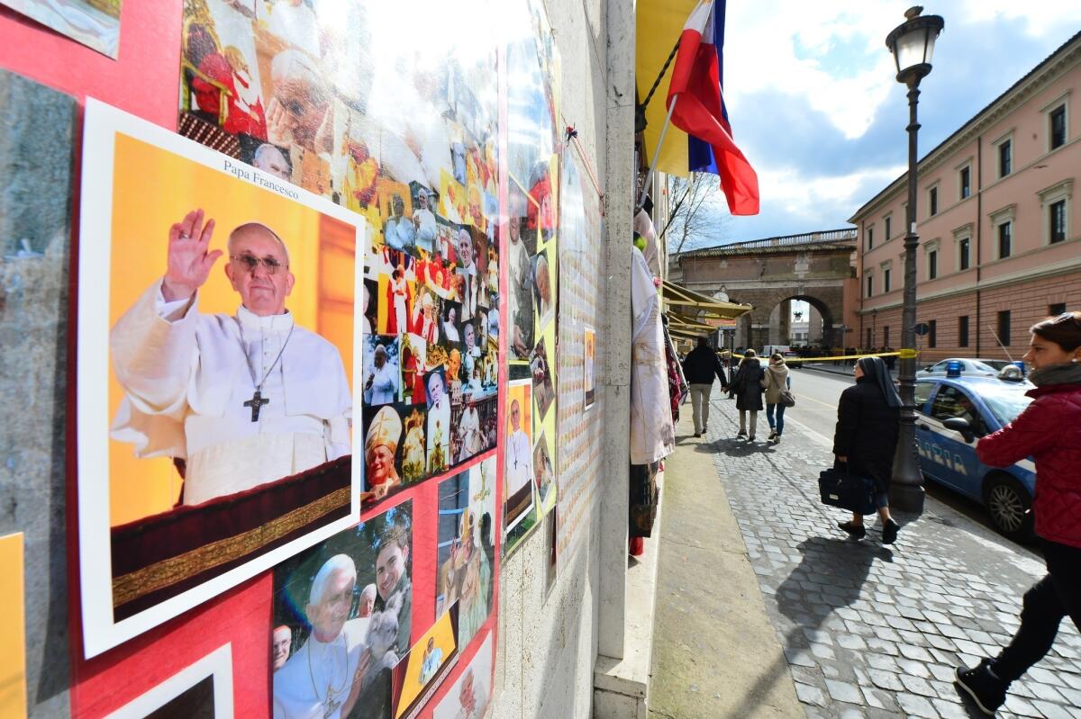 A woman walks past a picture of Pope Francis Friday at the Vatican.