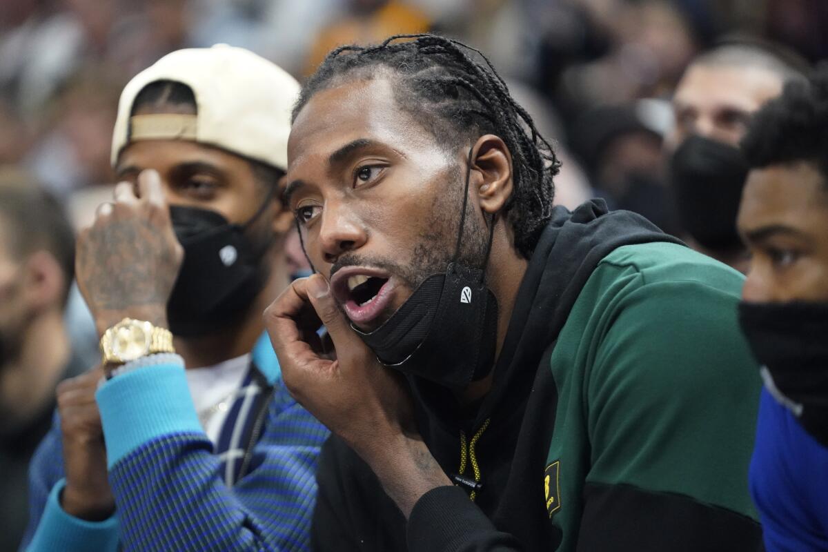 Clippers stars Paul George and Kawhi Leonard look on from the bench.